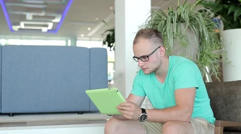 Young man writing a message on tablet from hotel lobby. Stock-Footage 54945490