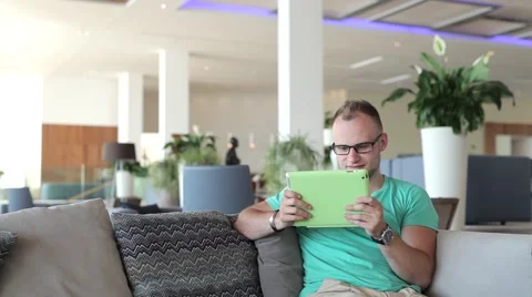 Young man writing a message on tablet from hotel lobby. Stock Footage 54945568