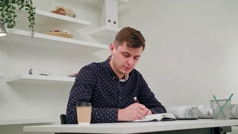 A Young Man Writing in a Notebook Indoors. Stock Footage 83834007