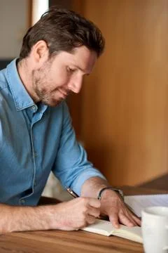 Young man writing in a notebook while working from home Foto stock