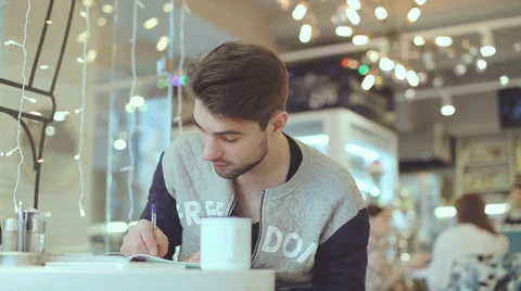 Young man writing in notepad in cafe Stock Footage 58646275