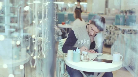 Young man writing in notepad in cafe, static shot Stock Footage 58656125