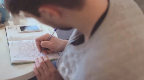 Young man writing in notepad in cafe Stock Footage 65741930