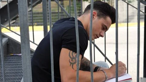 Young man writing on paper sheet with pen Stock Photos