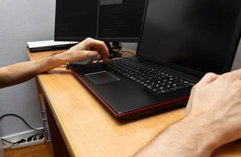 A young man writing programming code on laptop computer. Programmer profession Stock Photos