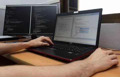 A young man writing programming code on laptop computer. Programmer profession Stock Photos