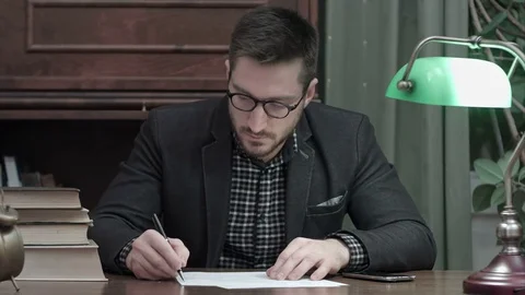 Young man writing something and being distracted by a phone call Video stock 73686126