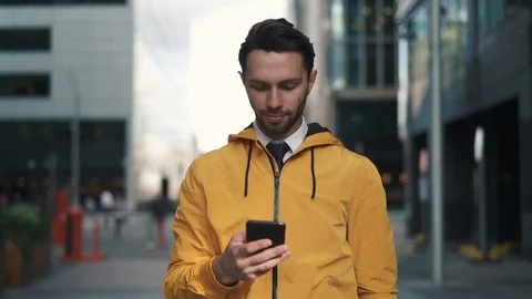 Young man in yellow jacket dialing a number and talking walking in summer street Stock Footage 95591499