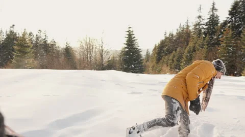 Young man in a yellow winter coat playfully running through deep snow in a Vídeo Stock 341037352
