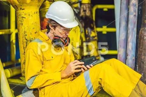 Young man in a yellow work uniform, glasses and helmet in industrial environment Stock Photos
