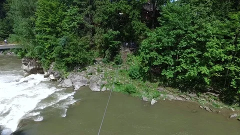 Young man on a zip line over the mountain river in Carpathians Stock Footage 114180107