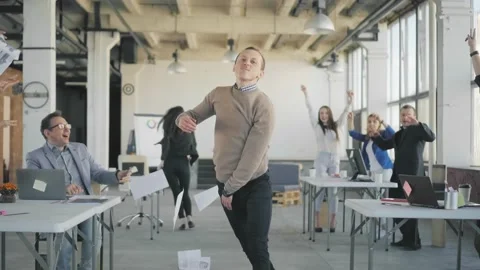 A young manager enters the office, dances, scatters documents. Colleagues get up Stock Footage 165385676