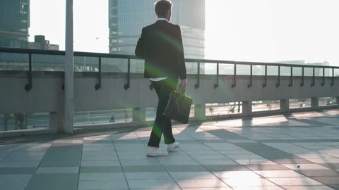 Young manager go over the bridge in the city against the background of the 스톡 동영상 165384361
