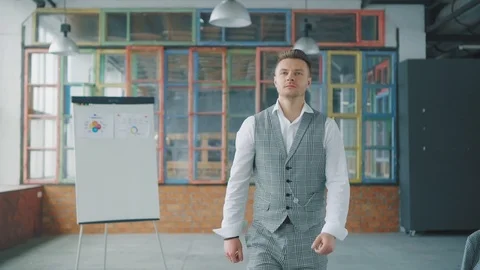 A young manager pranks in the office, walks up to a colleague, sits down at his Stock Footage 107981311