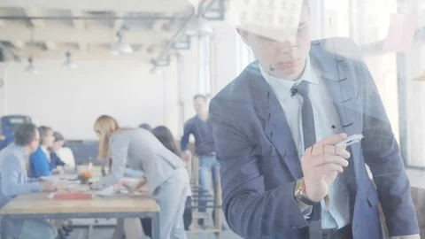 A young manager prepares a presentation and draws graphics on a glass board with Stock Footage 109563500