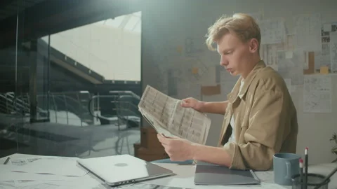 Young Manager is Seated at Desk, Focused on Reading Newspapers at the Office Stock Footage 239110032