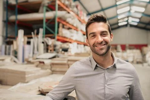 Young manager smiling while standing in a large warehouse Stock Photos