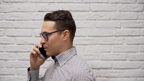 Young Manager talking with client on mobile phone on a white wall background. Stock Footage 127782904
