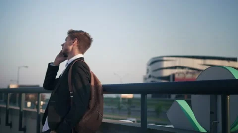 Young manager talking on the phone on the bridge. Sunrise in the city Stock Footage 134149711