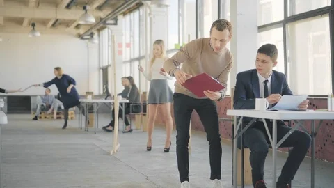 A young manager walks around the office, communicates with colleagues, and gives Stock Footage 108872692