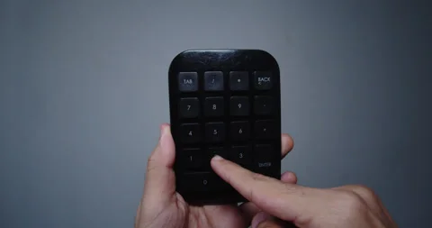Young man's hand holding a small black calculator or mini computer numeric 库存影片 295364329