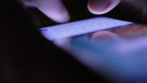 Young man's hand texting and typing on his phone in the dark 스톡 동영상 201409489