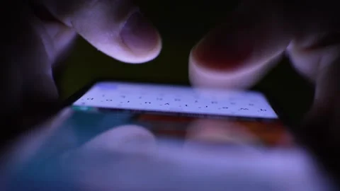 Young man's hand texting and typing on his phone in the dark Stock Footage 201409565