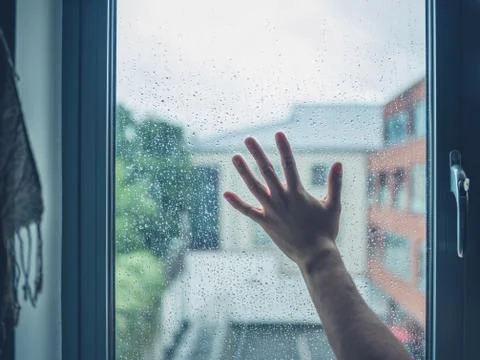 Young man's hand touching window with dew 스톡 사진