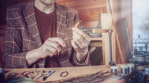 Young man's hands tying a fly for fishing Stock Photos
