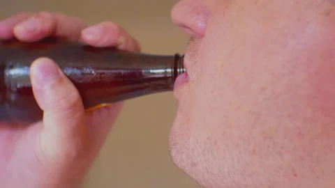 A young man's mouth drinking from a brown glass beer bottle Stock Footage 282026845