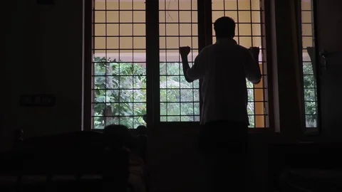 A young man's silhouette in front of the window loneliness alone black and white Stock Footage 127687056