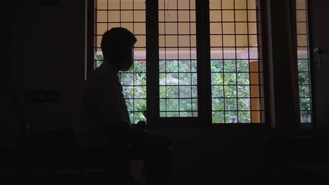 A young man's silhouette in front of the window loneliness alone black and white Video stock 127687117