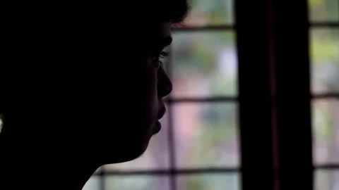 Young man's silhouette in front of window close up cinematic loneliness alone Stock Footage 127688030