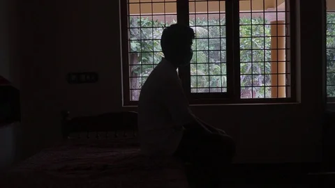 A young man's silhouette in front of the window loneliness alone black and white Stock Footage 127688215