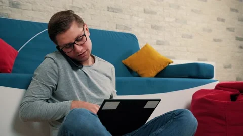 Young mantalking at the phone while write a message on laptop, isolated at home. Stock Footage 146072429