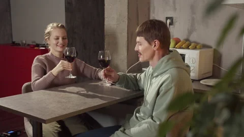 A young married couple drinks red wine in their kitchen, makes a toast and Stock Footage 145068537