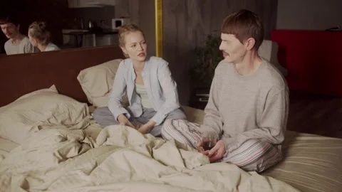 A young married couple drinks their morning coffee from glass mugs right in bed Stock Footage 145080336