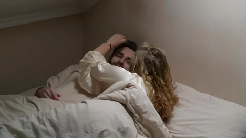 Young married couple lying in bed and talking in the morning. 库存影片 329939736