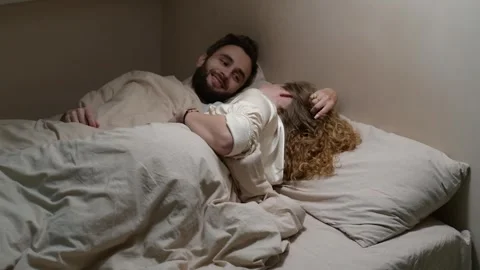 Young married couple lying in bed and talking in the morning. 库存影片 329939746