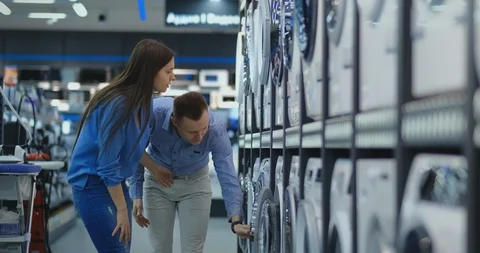 Young married couple man and woman in casual clothes appliances store choose to Stock Footage