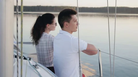 Young married couple in red pants sits on the side of a white sailing yacht 库存影片 119051833