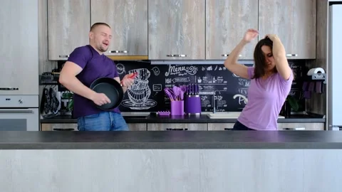 Young married spouse using frying pan as guitar, pretending to be musician Stock Footage 208709284