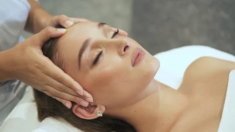Young masseuse making face massage to her client in salon Stock Footage 111026059