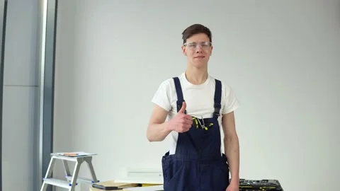 Young master in work uniform and with a set of tools stands on a white wall Stock Footage 147040557