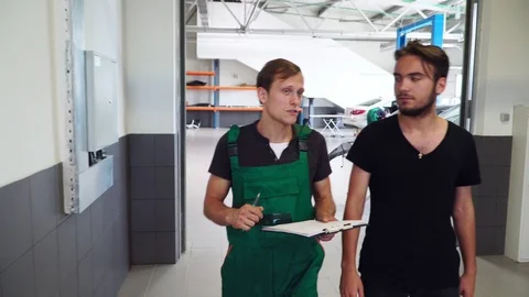 A young mechanic communicates with a client in an auto service. Stock Footage 94655405