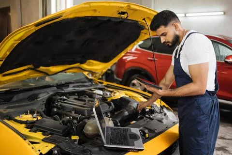 Young mechanic using tablet recording automobile engine checks collect detailed Foto stock