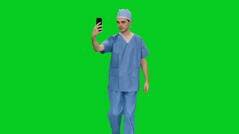 Young medic in uniform having a videochat while walking on green screen Stock Footage 126341046