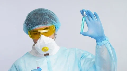 Young medical chemist analyzing test tube with blue liquid in protection suit Stock Footage 127035642