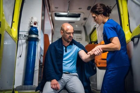 A young medical worker checking the traumatized hand of her patient in an Foto stock