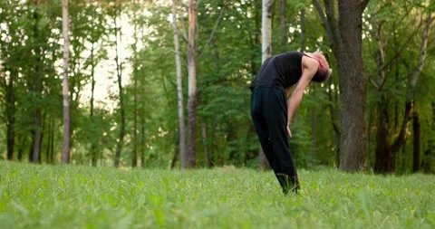 Young Men in black clothes practicing yoga and meditating in park at sunny Stock Footage 157736711